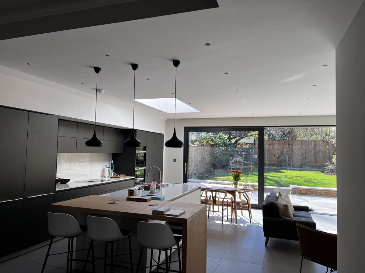 Open-plan kitchen with an island and sliding doors to the garden, Montolieu Gardens, Putney