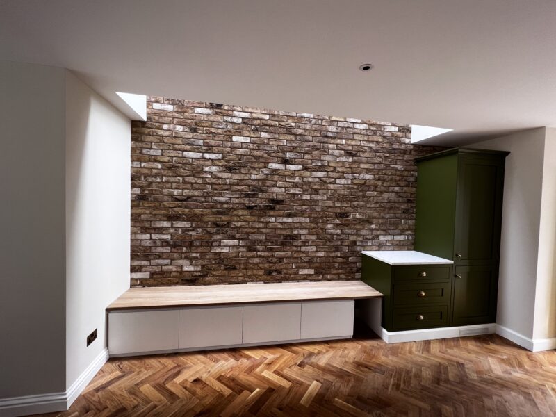 Bespoke built-in bench seating and cabinet against an exposed brick wall