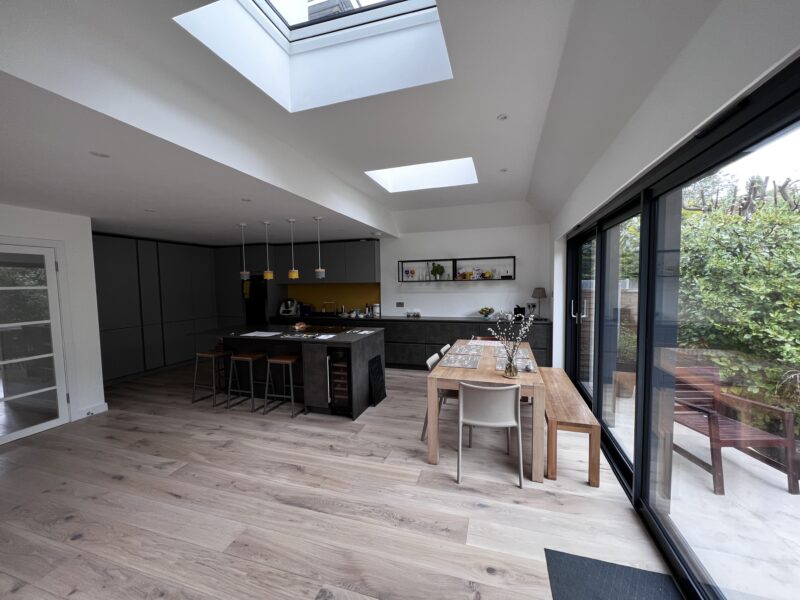 Open-plan kitchen and dining room with rooflights and full-width sliding doors in a Kingston extension
