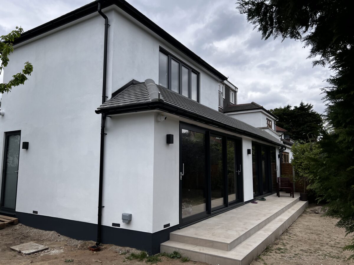 Side view of a white rear and side extension with a raised terrace in Kingston