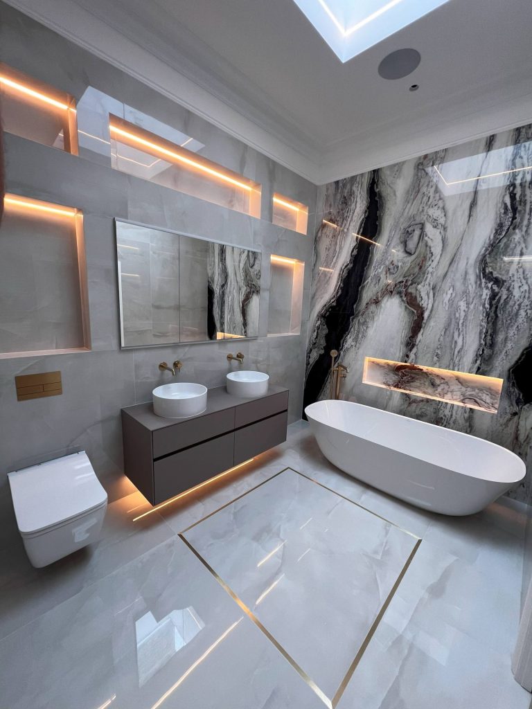 Bathroom with freestanding bath, twin basins, stone-effect feature wall and concealed lighting