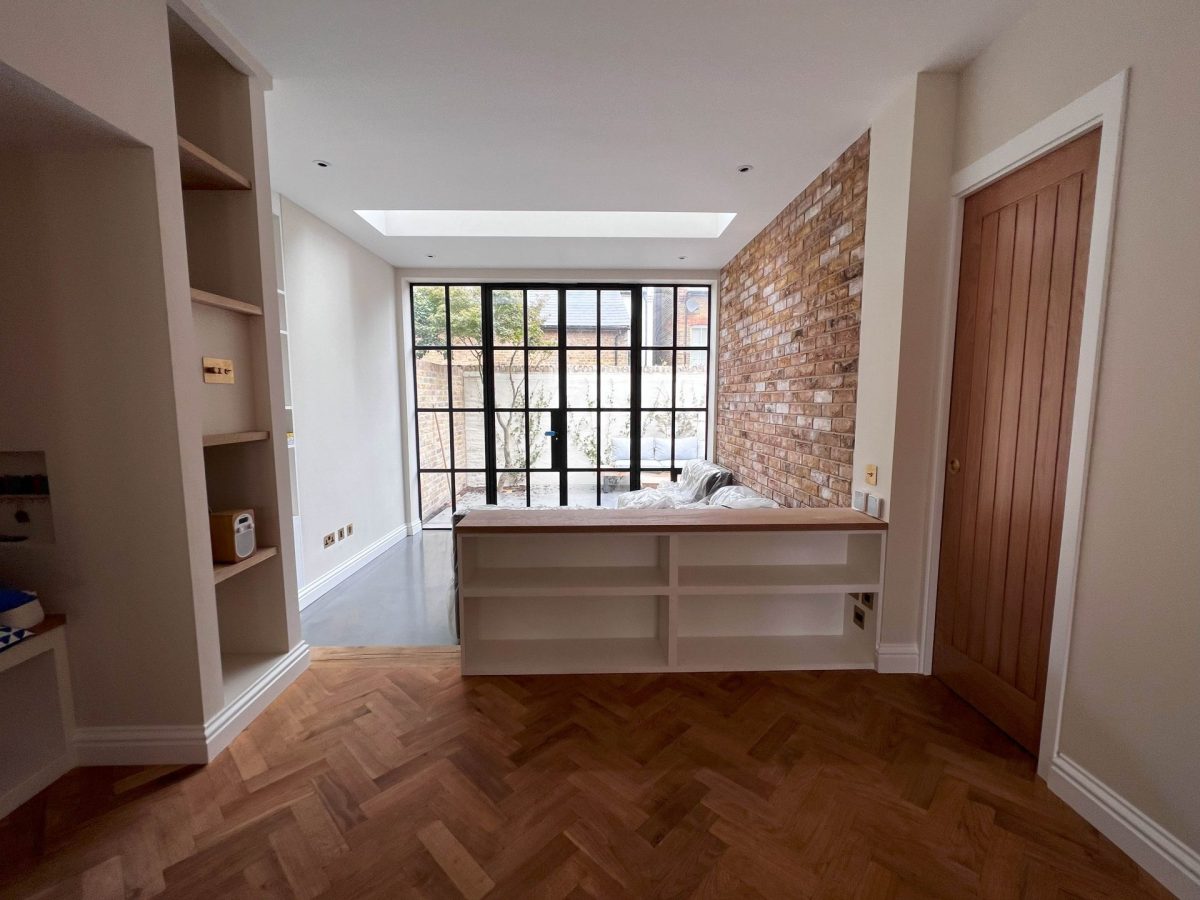 Black-framed internal glazing, window seat and built-in shelving on a herringbone floor