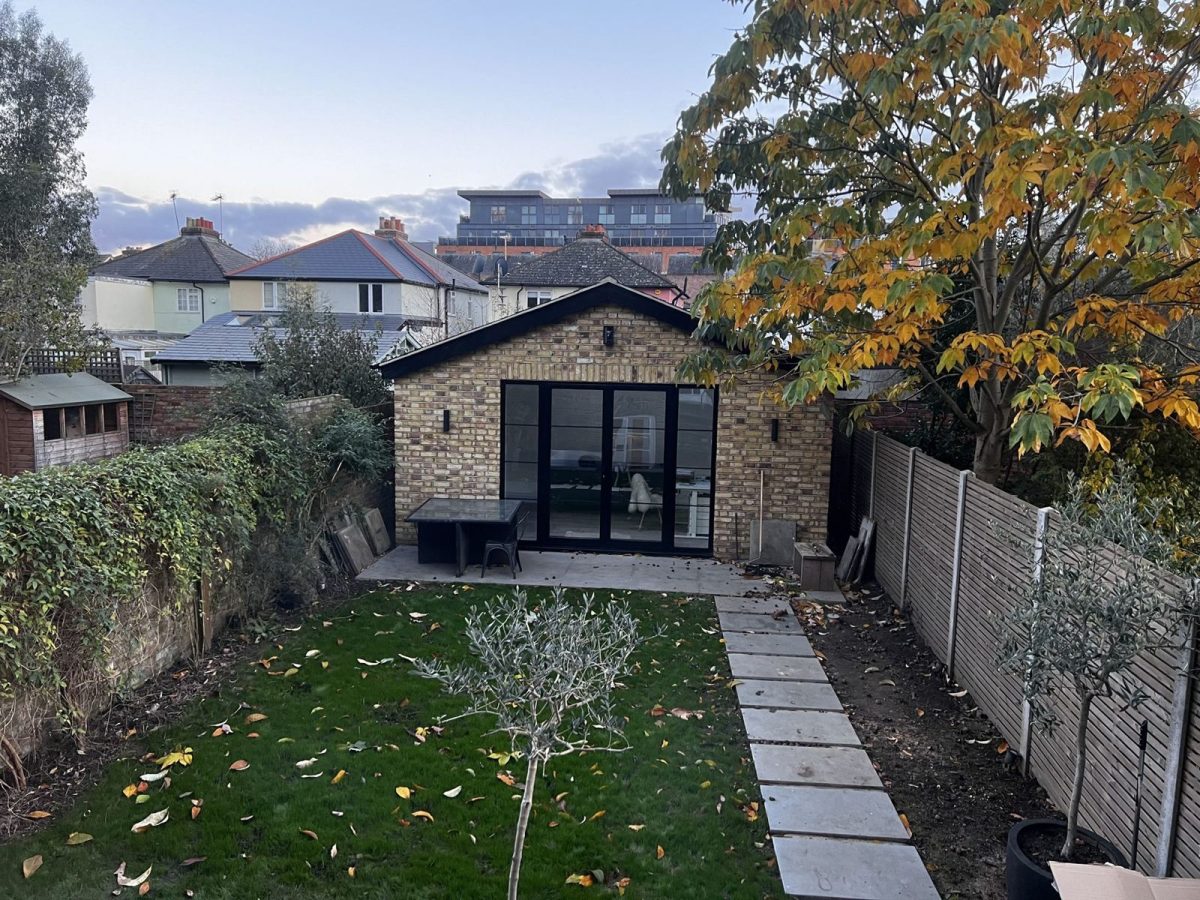 Detached brick garden office with black-framed glazed doors at the end of a Surbiton garden