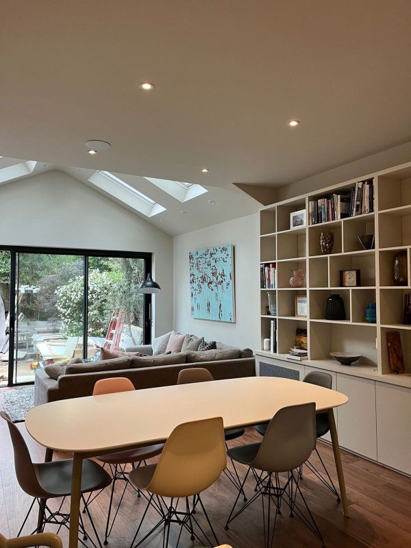 Dining and living space with vaulted ceiling, rooflights and fitted shelving
