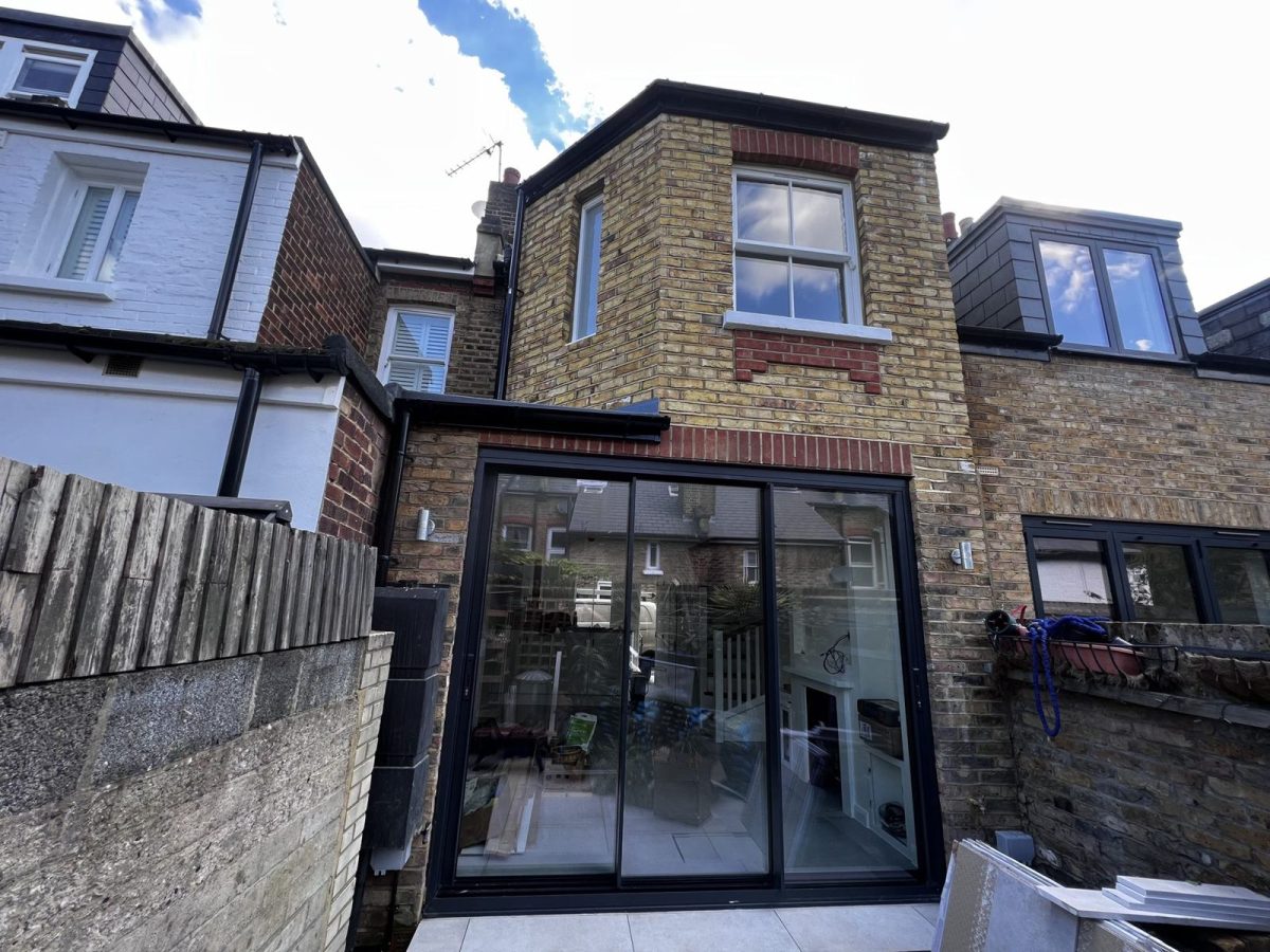 Brick rear extension with slim black-framed sliding doors on a Victorian terraced house in Richmond