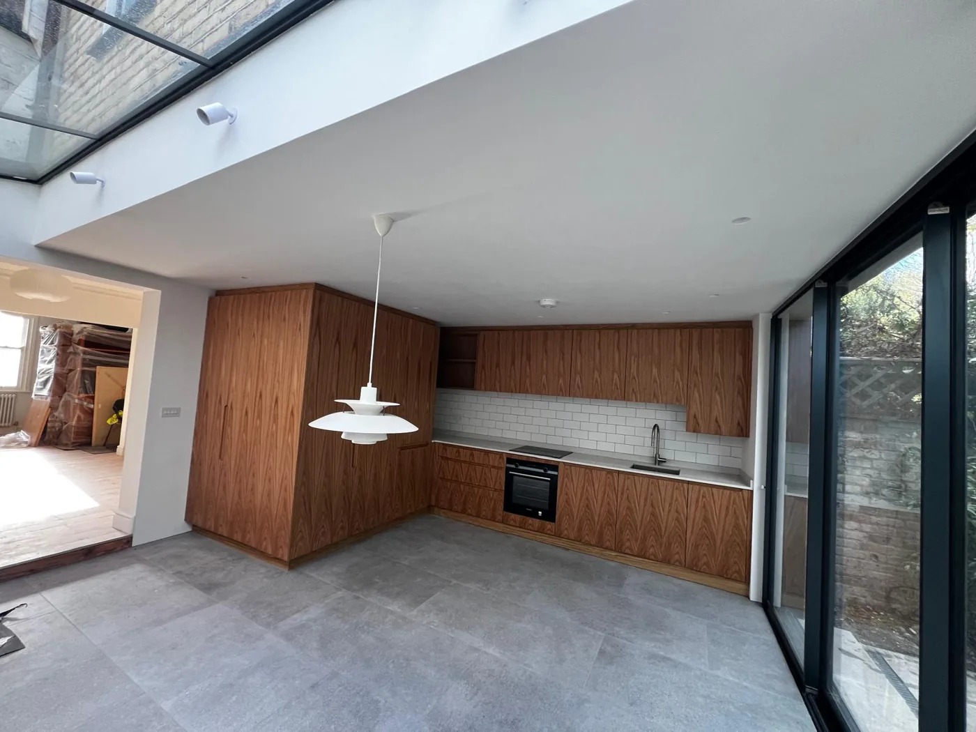 Timber-veneer kitchen with white metro tiles under a glazed roof, Denmark Road, Wimbledon