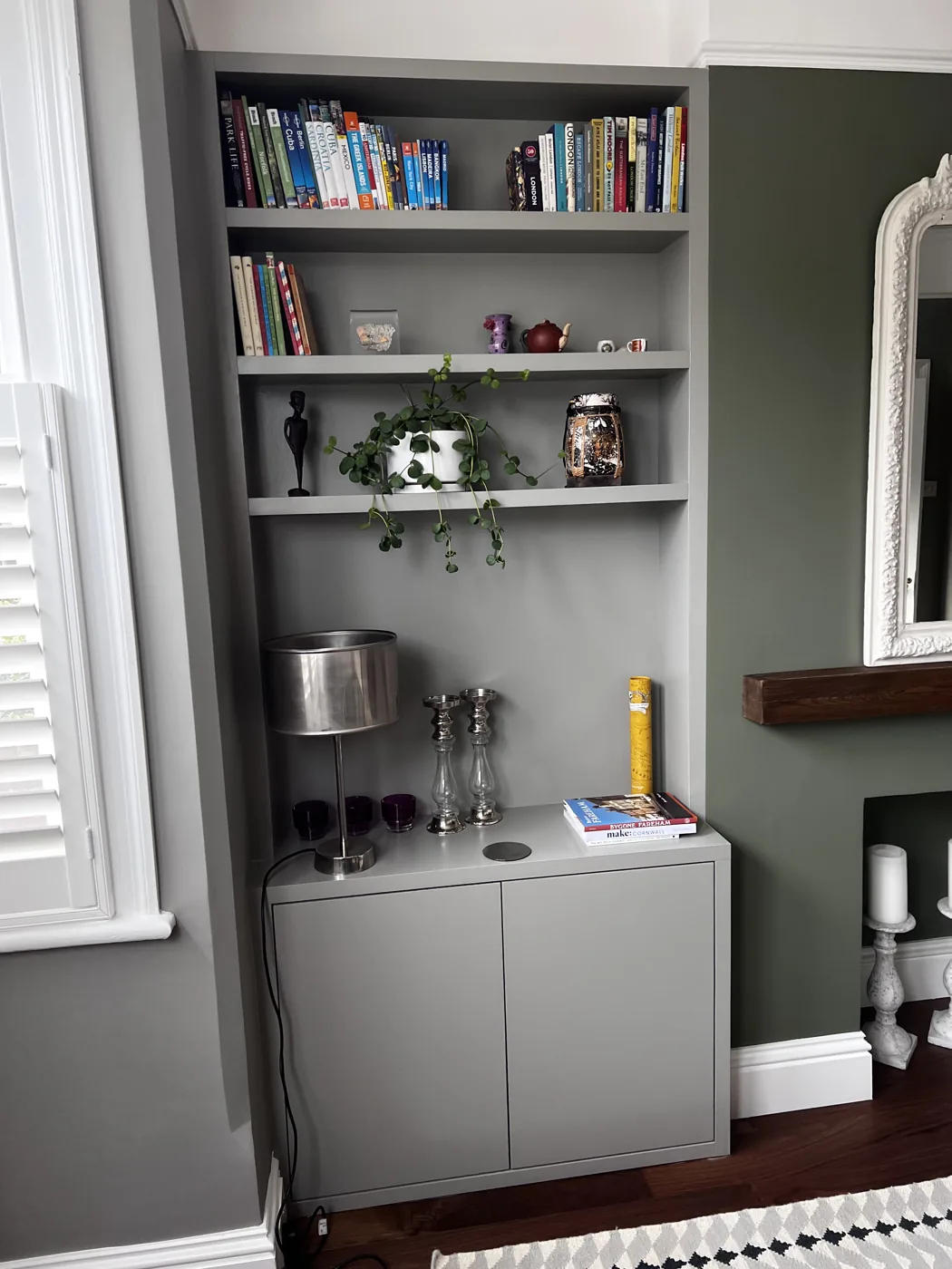 Painted alcove cupboard with floating shelves beside a chimney breast