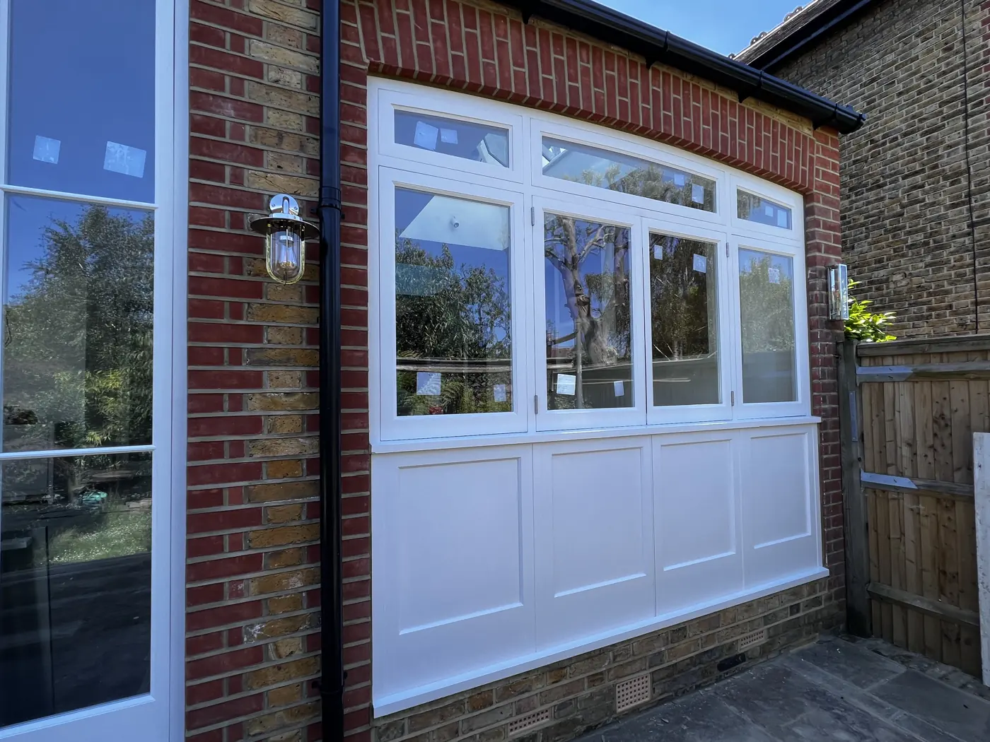Painted timber glazing with a panelled base in a brick rear bay