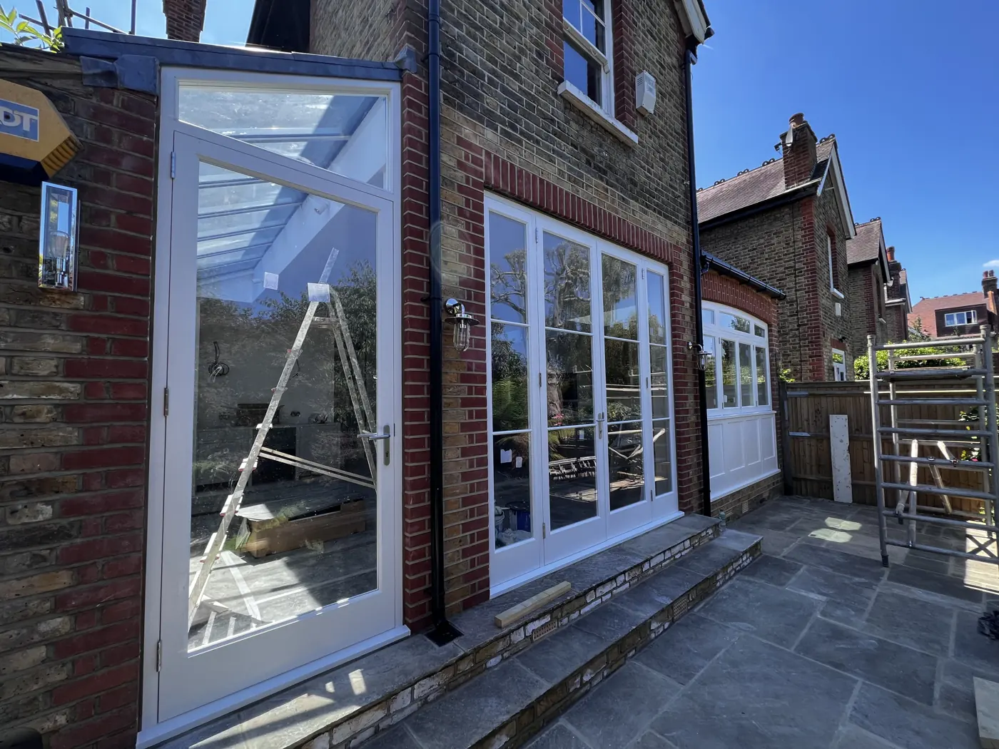 White timber-framed glazed doors and windows on a brick period house