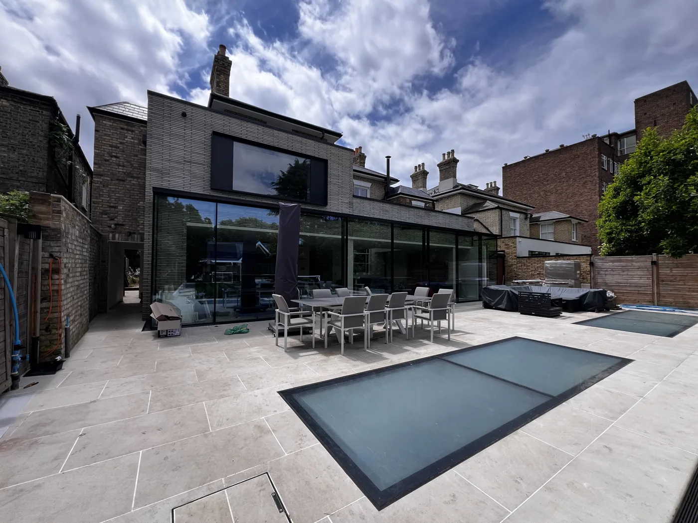Rear of a renovated house with full-width glazing and a stone terrace, Upper Richmond Road, Putney