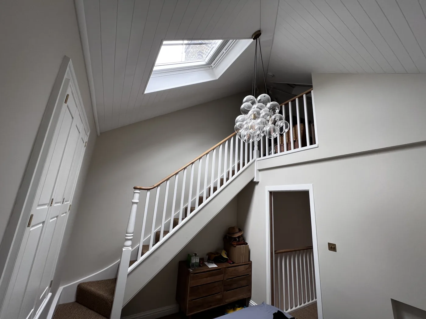 Painted staircase and landing lit by a rooflight in a sloping ceiling